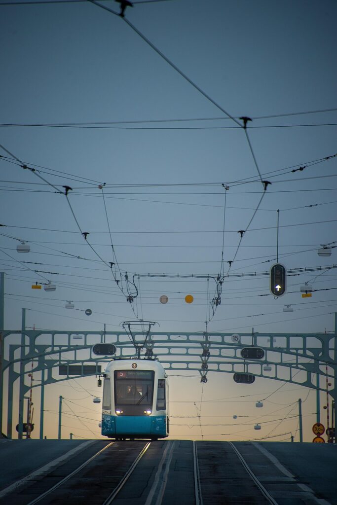 Tram in Sweden with wires at the top of the image and a tram car in the left center of the image that is white and blue.
Image on the Home - SARA page