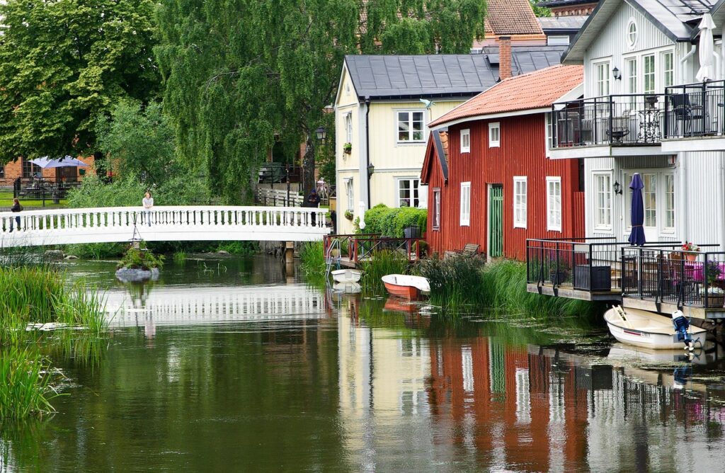 Sweden water channel with red house and white house on right side of water and a white bridge.
image on the Publications page